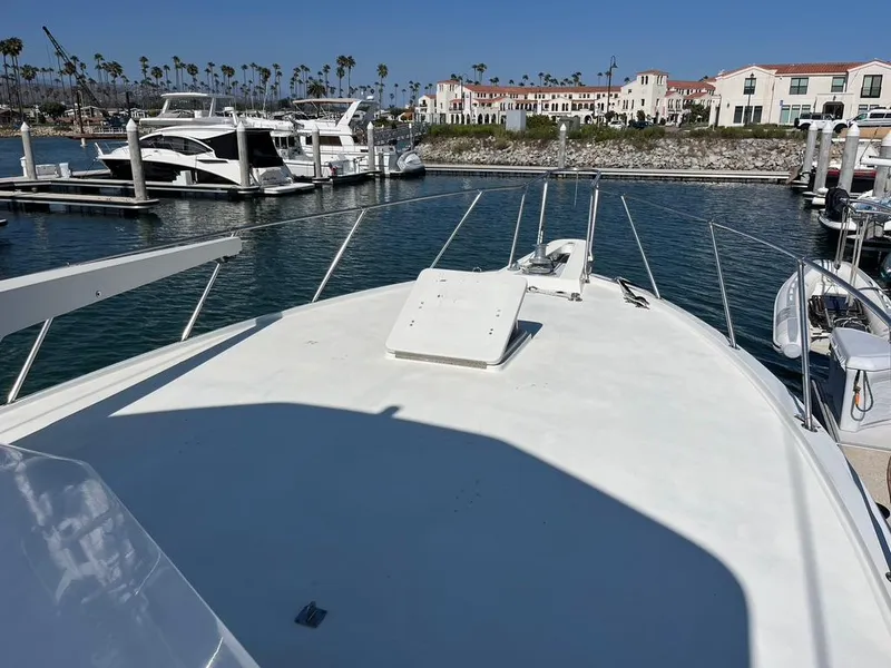 Slide: The Image of 1988 Hatteras 52 Convertible yacht docked in a marina with waterfront buildings. - 6