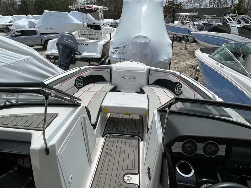 Slide: The Image of 2018 Yamaha Boats 212X interior with seating and dashboard, surrounded by covered boats. - 15
