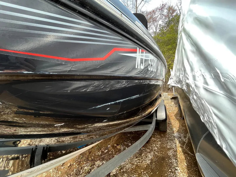 Slide: The Image of 2018 Yamaha Boats 212X on trailer, black hull with red accents, parked outdoors. - 3