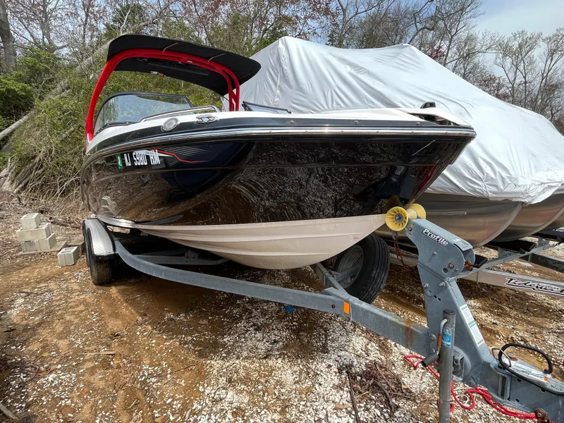Slide: The Image of 2018 Yamaha Boats 212X on trailer, parked outdoors, partially covered, ready for transport. - 6