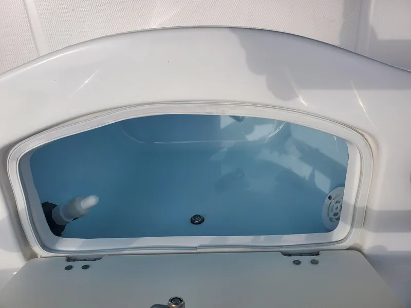 Slide: The Image of 2022 Robalo R222 Center Console livewell, open lid, white interior, blue water. - 18