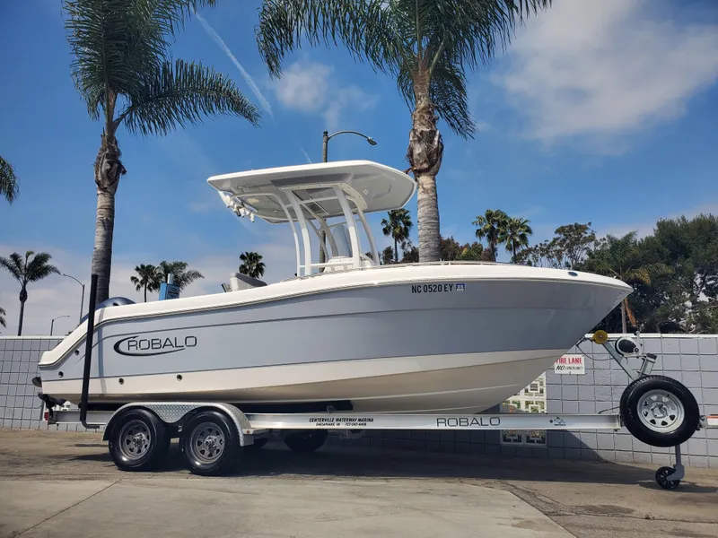 Slide: The Image of 2022 Robalo R222 Center Console boat on trailer, parked near palm trees. - 20