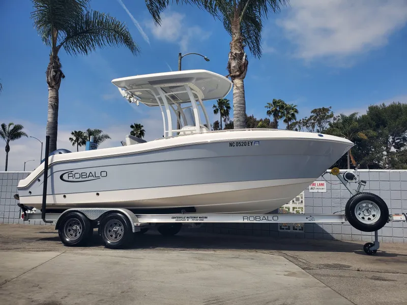 Slide: The Image of 2022 Robalo R222 Center Console boat on trailer, parked near palm trees. - 21