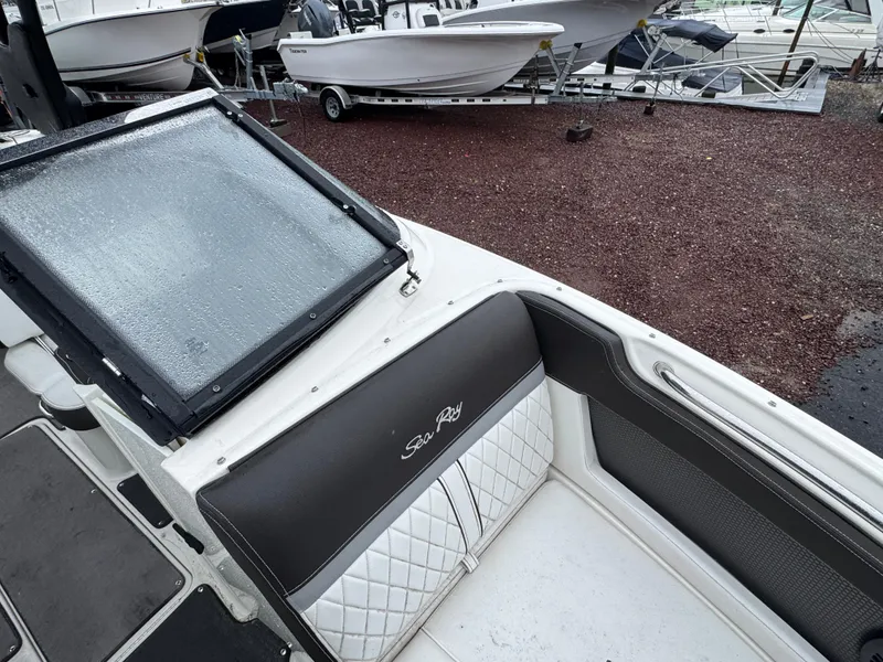 Slide: The Image of 2017 Sea Ray SLX 230 boat interior with sleek seating and windshield, parked on a gravel lot. - 15
