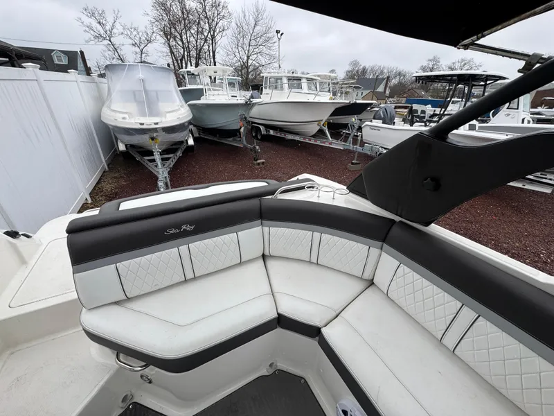 Slide: The Image of 2017 Sea Ray SLX 230 boat interior with white and black seating, parked among other boats. - 5