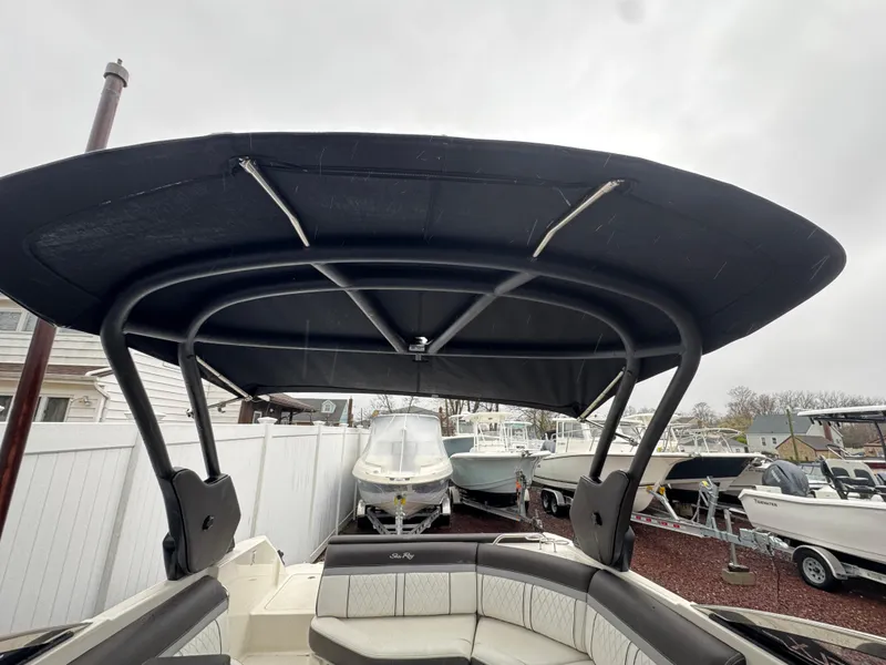 Slide: The Image of 2017 Sea Ray SLX 230 boat with black canopy, docked among other boats. - 7