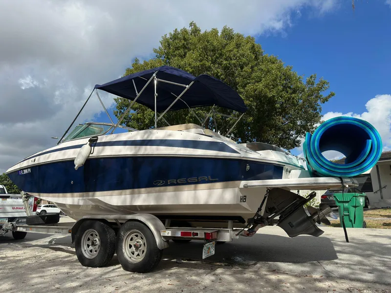 Slide: The Image of 2013 Regal 24 FasDeck boat on trailer with blue canopy and rolled-up mat. - 0