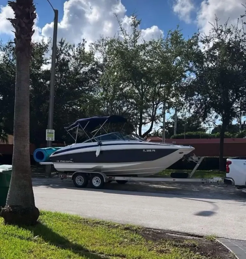 Slide: The Image of 2013 Regal 24 FasDeck boat on trailer, parked on street under cloudy sky. - 1