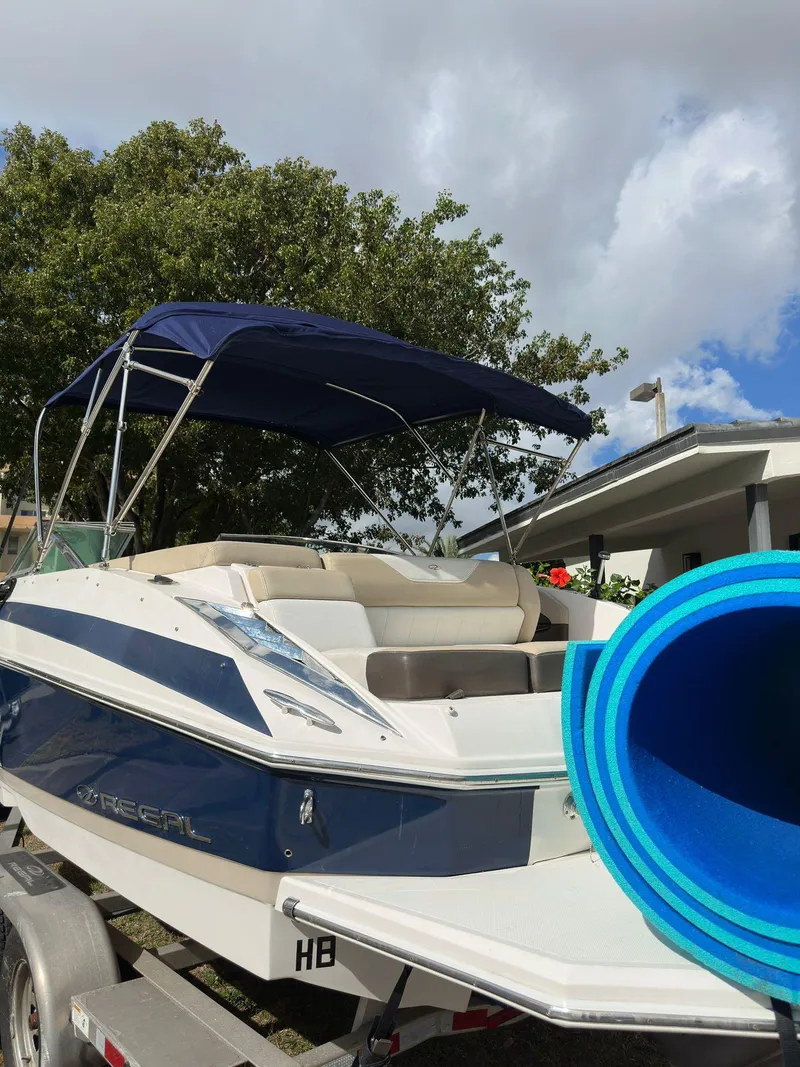 Slide: The Image of 2013 Regal 24 FasDeck boat with blue canopy and rolled-up mat on trailer. - 10