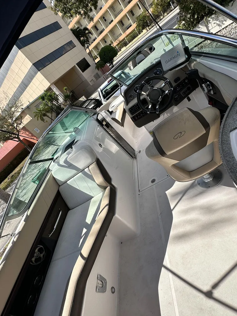 Slide: The Image of 2013 Regal 24 FasDeck boat interior with seating and steering wheel, docked near buildings. - 12