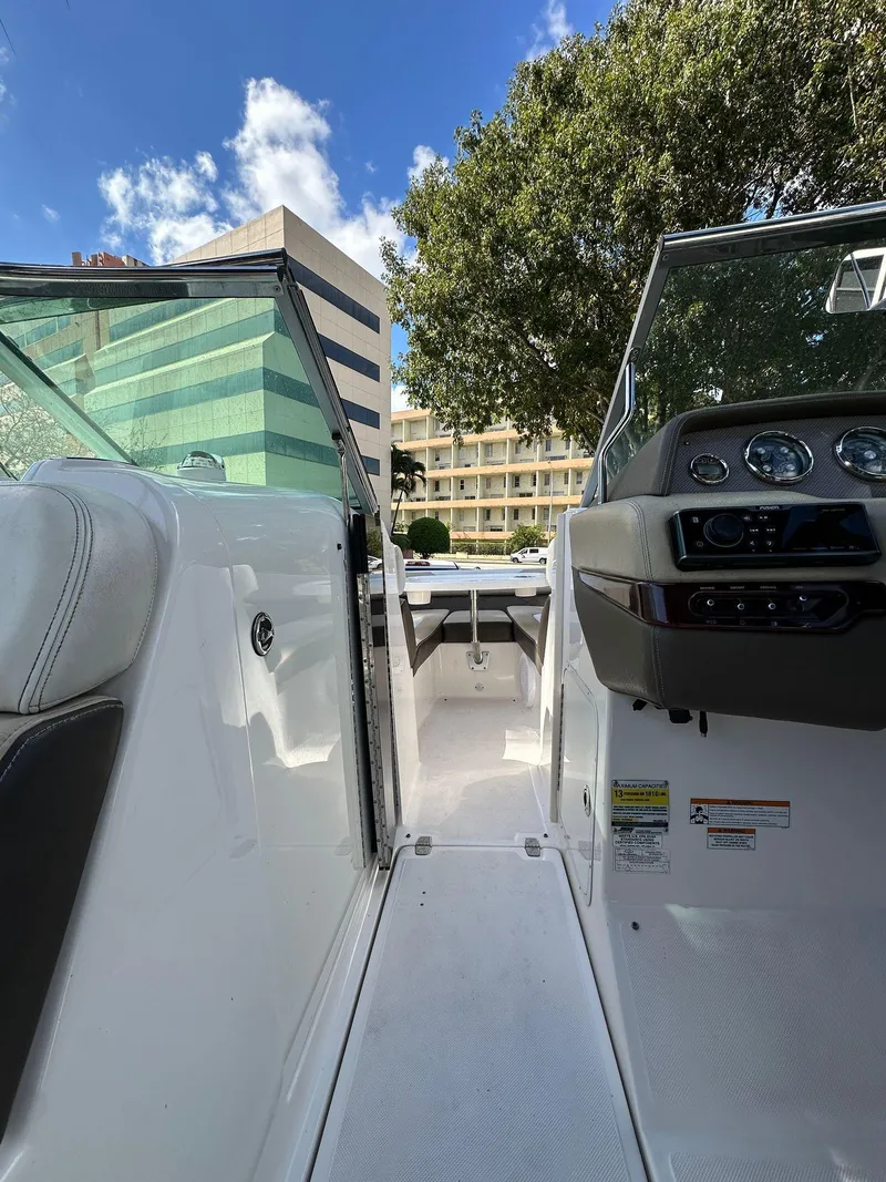 Slide: The Image of 2013 Regal 24 FasDeck boat interior with dashboard, city buildings, and blue sky background. - 5