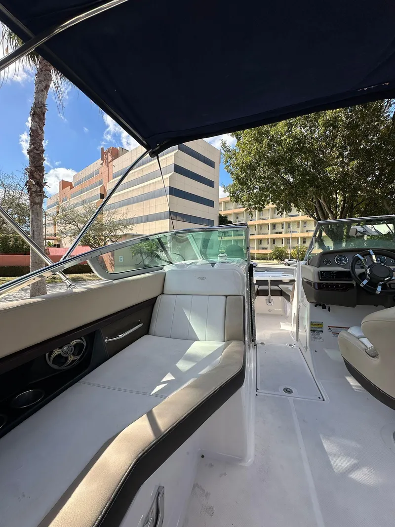 Slide: The Image of 2013 Regal 24 FasDeck boat interior with seating, canopy, and cityscape background. - 6