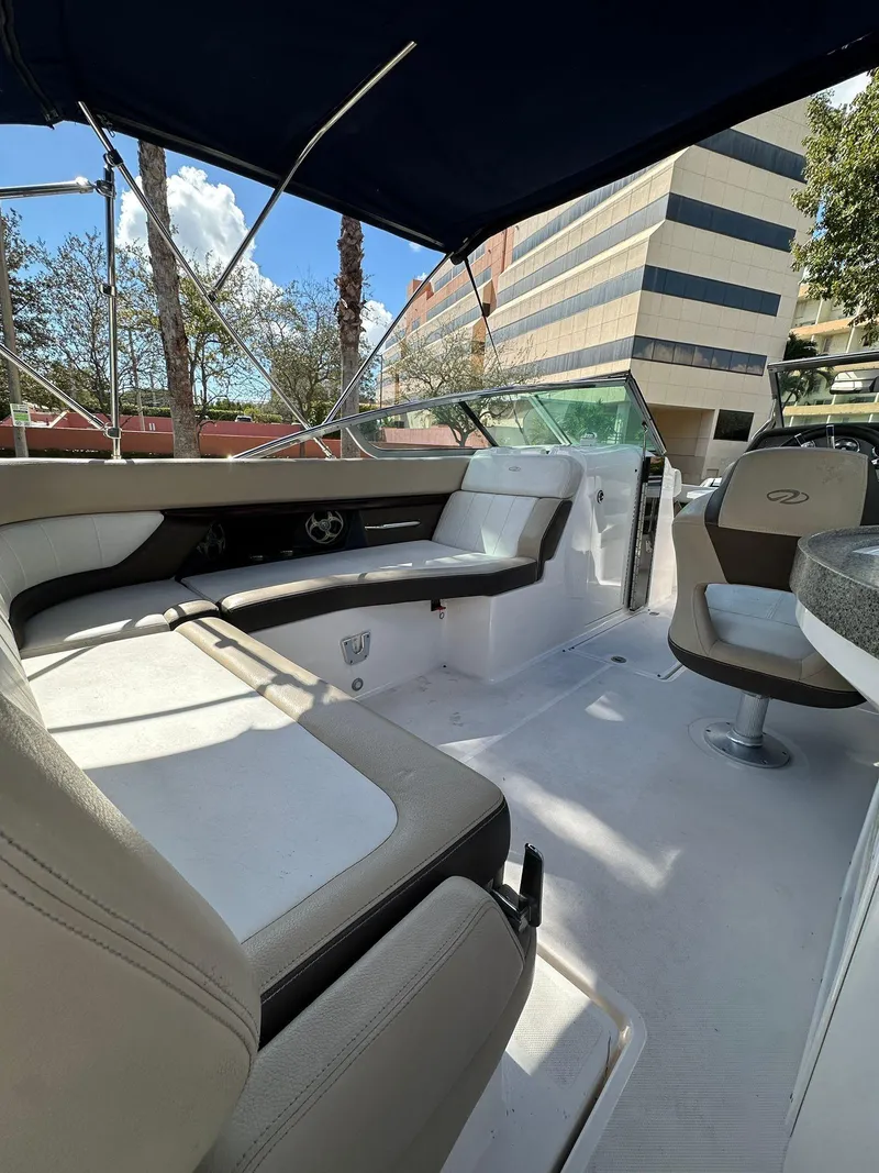Slide: The Image of 2013 Regal 24 FasDeck boat interior with seating and canopy, urban backdrop. - 7