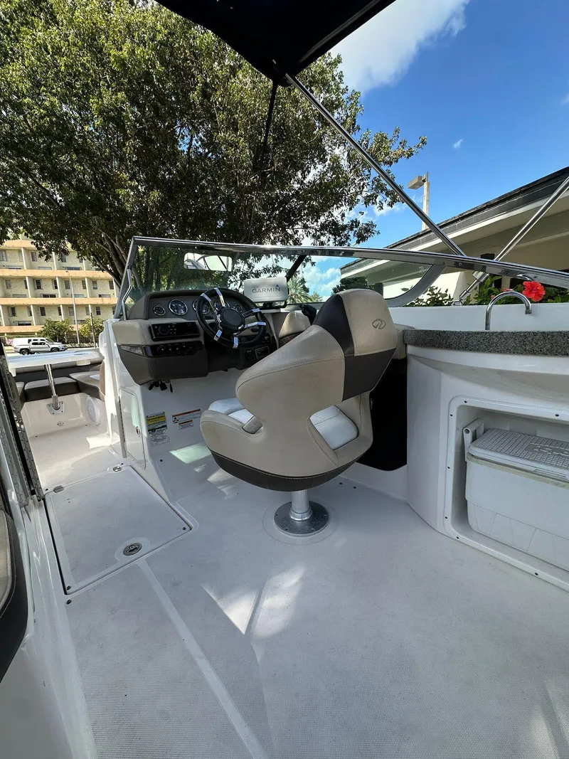 Slide: The Image of 2013 Regal 24 FasDeck boat interior with steering wheel and seating under a clear sky. - 8