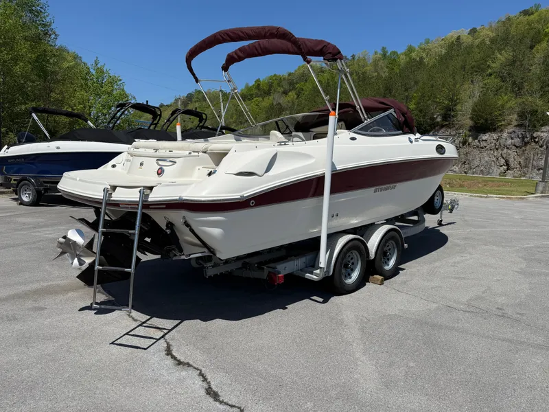 Slide: The Image of 2013 Stingray 235 CR boat on trailer, parked outdoors with scenic background. - 1