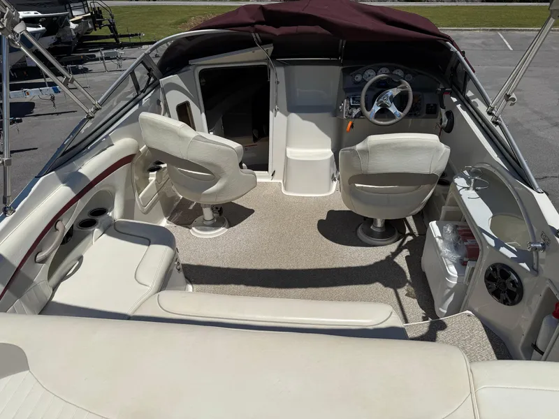 Slide: The Image of 2013 Stingray 235 CR boat interior with beige seating and steering console. - 15