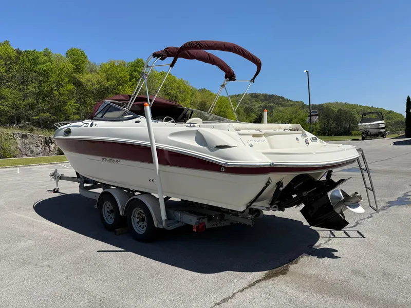 Slide: The Image of 2013 Stingray 235 CR boat on trailer, parked outdoors, sunny day. - 3