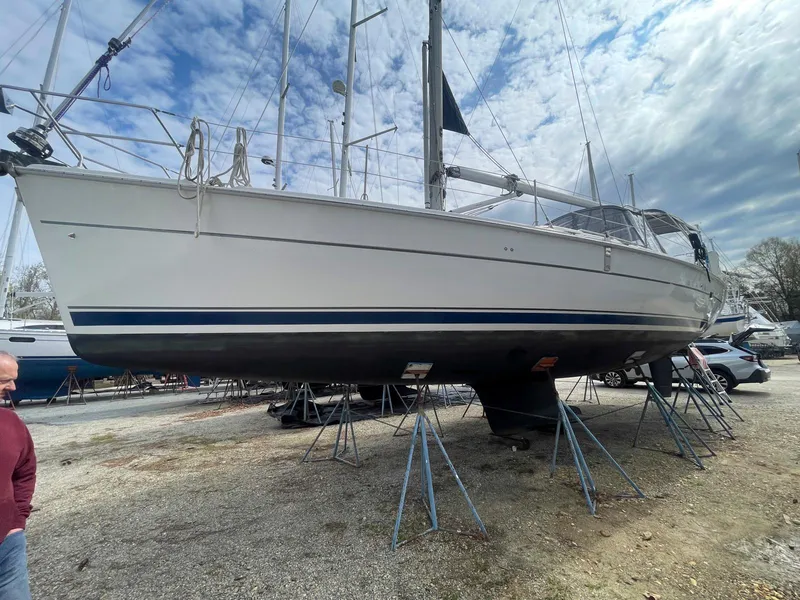 Slide: The Image of 2004 Hunter 44 Deck Salon sailboat on stands, under a partly cloudy sky. - 10