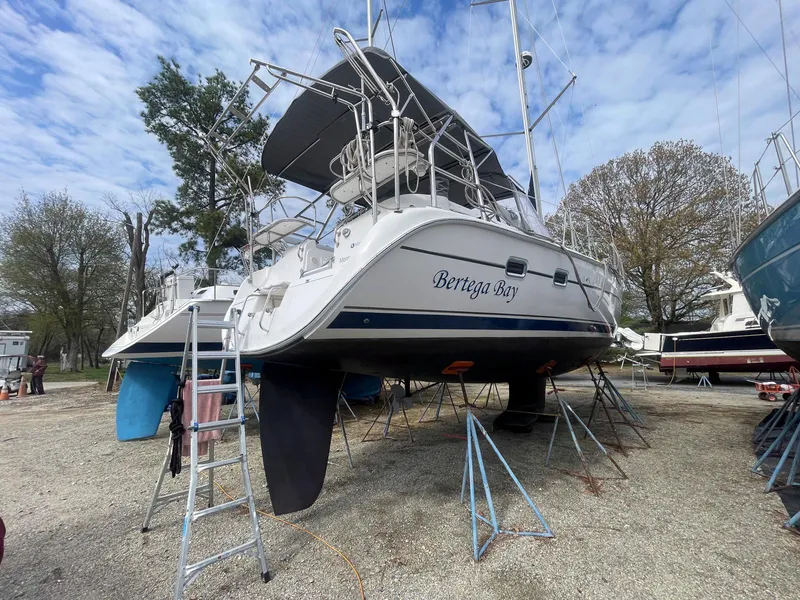 Slide: The Image of 2004 Hunter 44 Deck Salon sailboat on stands, named "Bertiga Bay," in a boatyard. - 11