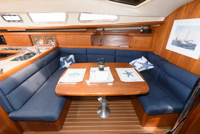 Slide: The Image of 2004 Hunter 44 Deck Salon interior with blue seating and wooden table. - 14