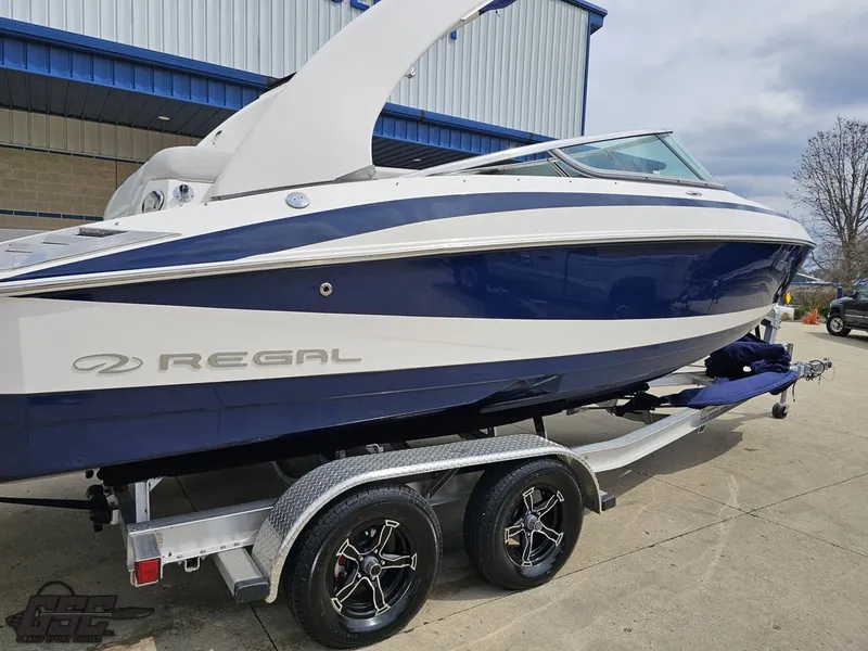 Slide: The Image of 2011 Regal 2500 Bowrider boat on trailer, blue and white design, parked outdoors. - 15