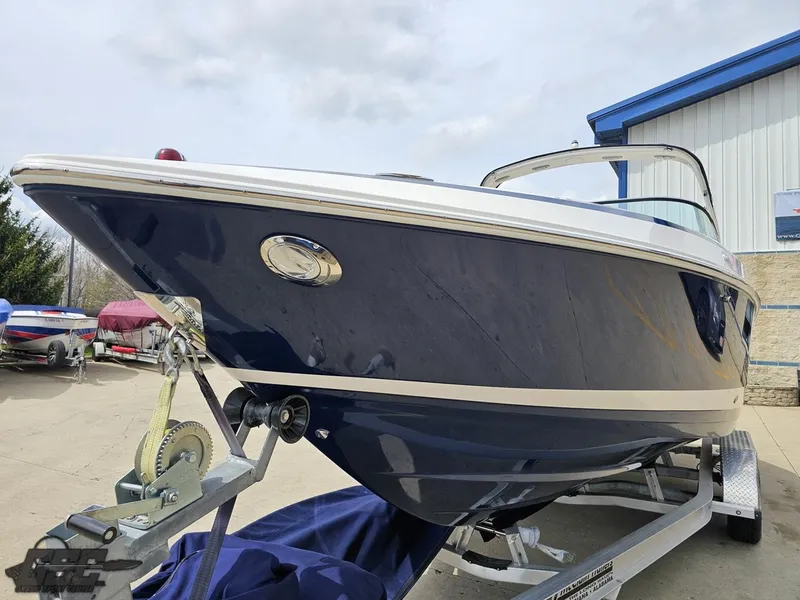 Slide: The Image of 2011 Regal 2500 Bowrider boat on trailer, blue hull, parked outdoors. - 21