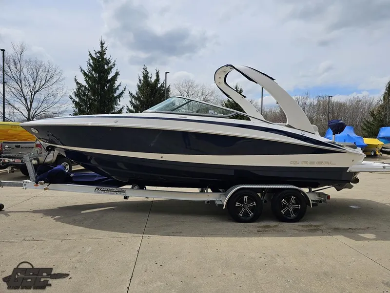 Slide: The Image of 2011 Regal 2500 Bowrider boat on trailer, parked outdoors, under cloudy sky. - 23