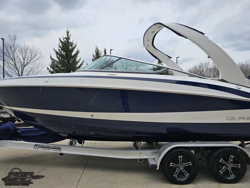 Slide: The Image of 2011 Regal 2500 Bowrider boat on trailer, blue and white design, parked outdoors. - 24