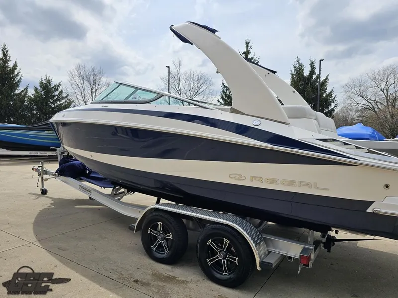 Slide: The Image of 2011 Regal 2500 Bowrider boat on trailer, parked outdoors, showcasing sleek design and modern features. - 31