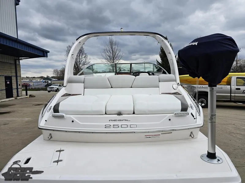 Slide: The Image of 2011 Regal 2500 Bowrider boat with white seating, docked outdoors under cloudy skies. - 38