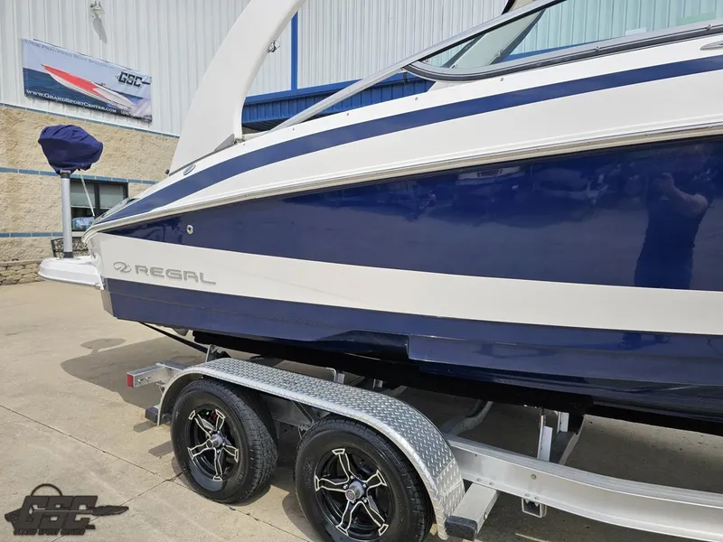 Slide: The Image of 2011 Regal 2500 Bowrider boat on trailer, blue and white design, parked outdoors. - 6
