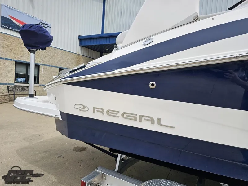 Slide: The Image of 2011 Regal 2500 Bowrider boat, blue and white, parked outside a building. - 7