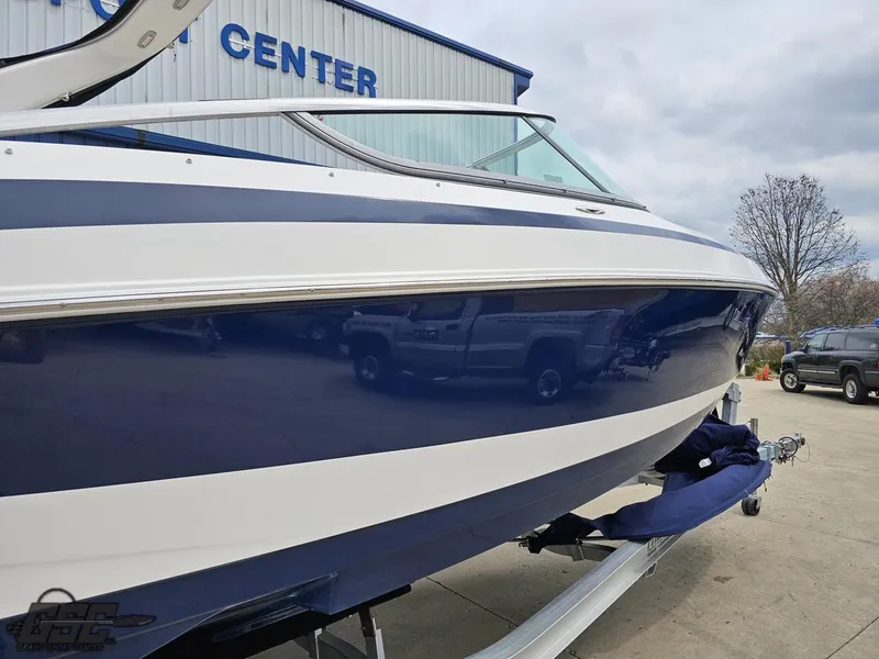 Slide: The Image of 2011 Regal 2500 Bowrider boat in blue and white, parked at a service center. - 8