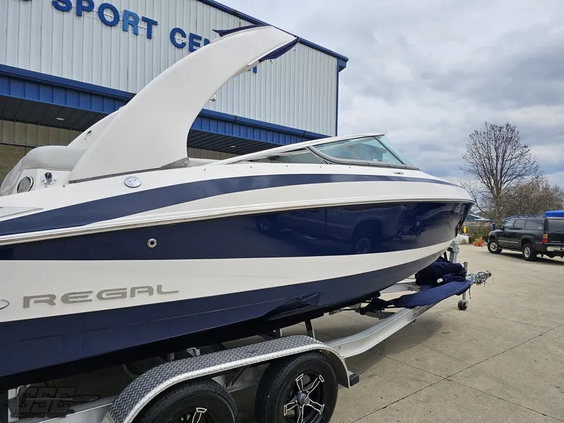 Slide: The Image of 2011 Regal 2500 Bowrider boat on trailer, parked outside a sports center. - 9