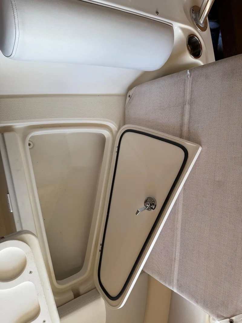 Slide: The Image of 2012 Edgewater 245 CX boat interior storage compartment with cushioned seating. - 13