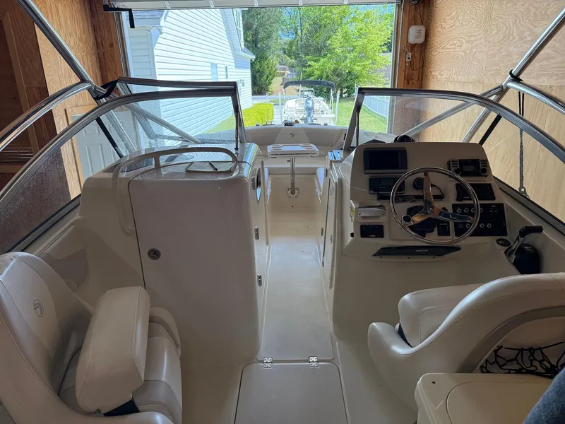 Slide: The Image of 2012 Edgewater 245 CX boat interior with steering wheel and seating, docked in a garage. - 3