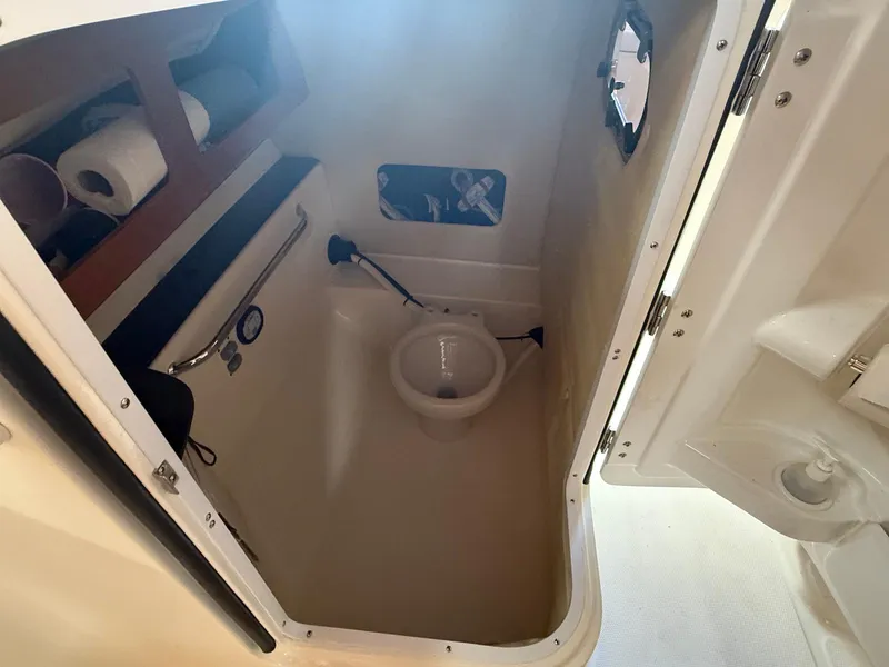 Slide: The Image of 2012 Edgewater 245 CX boat interior bathroom with toilet and storage shelves. - 30