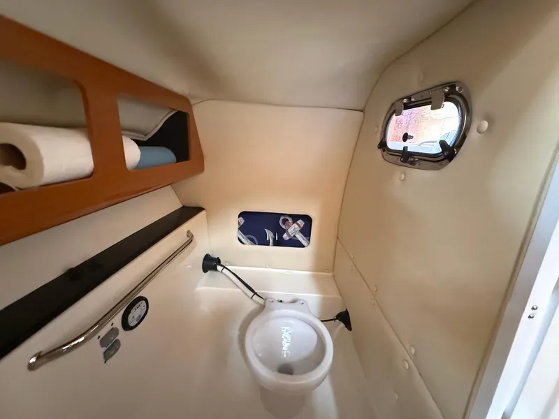 Slide: The Image of Interior of 2012 Edgewater 245 CX boat, featuring compact marine toilet and storage shelves. - 32