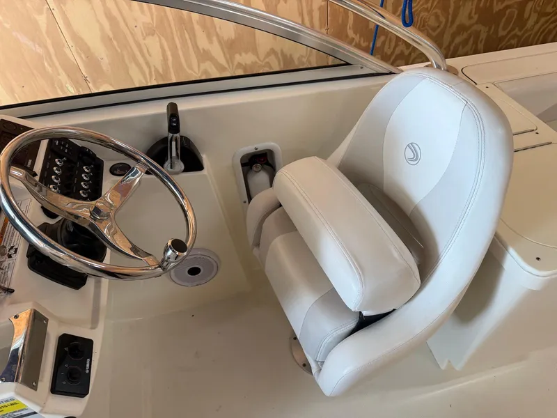 Slide: The Image of 2012 Edgewater 245 CX boat cockpit with white captain's chair and steering wheel. - 6