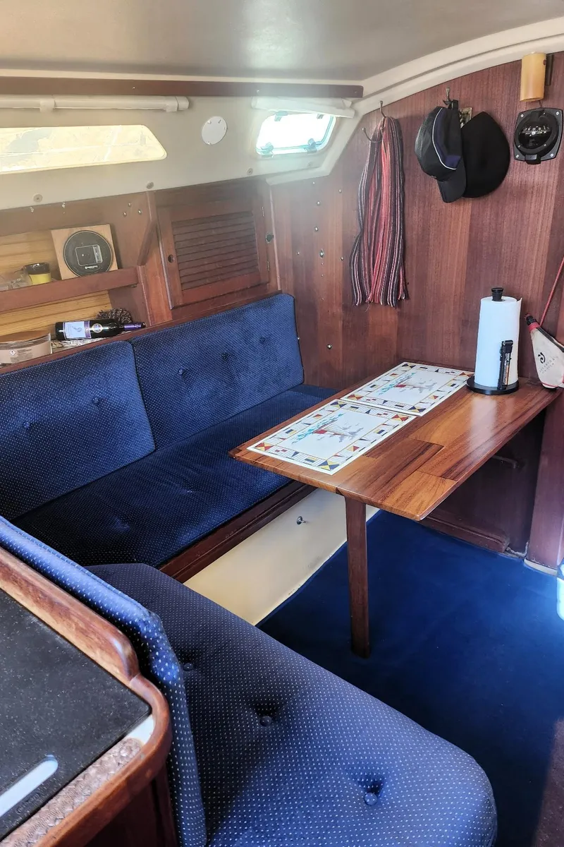 Slide: The Image of Interior of a 1987 Catalina 30 Mk II sailboat with blue seating and wooden table. - 12