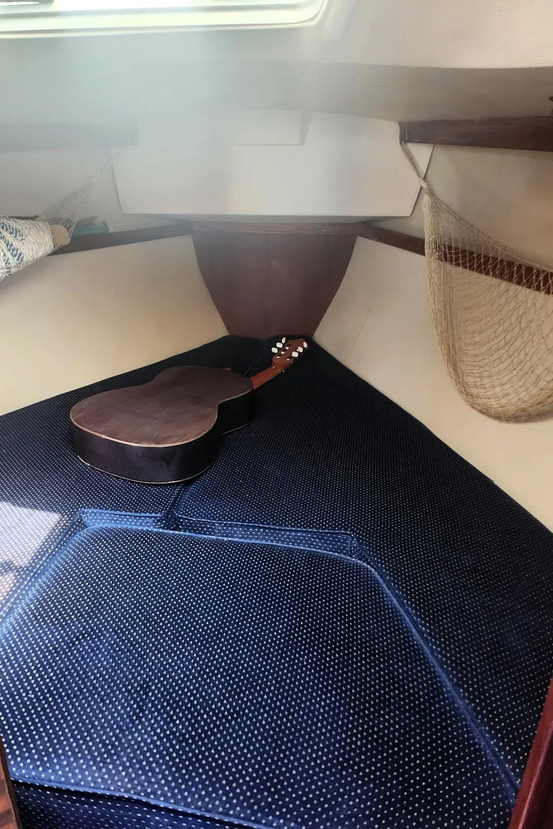 Slide: The Image of 1987 Catalina 30 Mk II cabin with guitar on blue cushioned bed. - 16