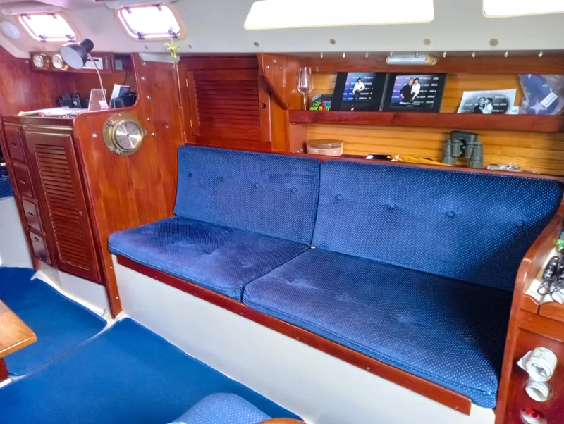 Slide: The Image of Interior of 1987 Catalina 30 Mk II sailboat with blue cushioned seating and wooden accents. - 23