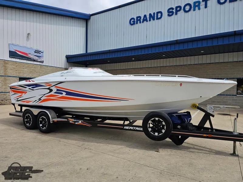 Slide: The Image of 2005 Baja 25 Outlaw speedboat on trailer, vibrant graphics, parked outside Grand Sport Center. - 12