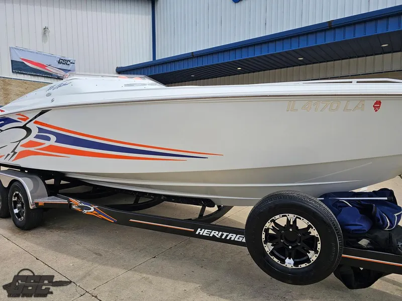 Slide: The Image of 2005 Baja 25 Outlaw boat on trailer with vibrant graphics, parked outside a building. - 13