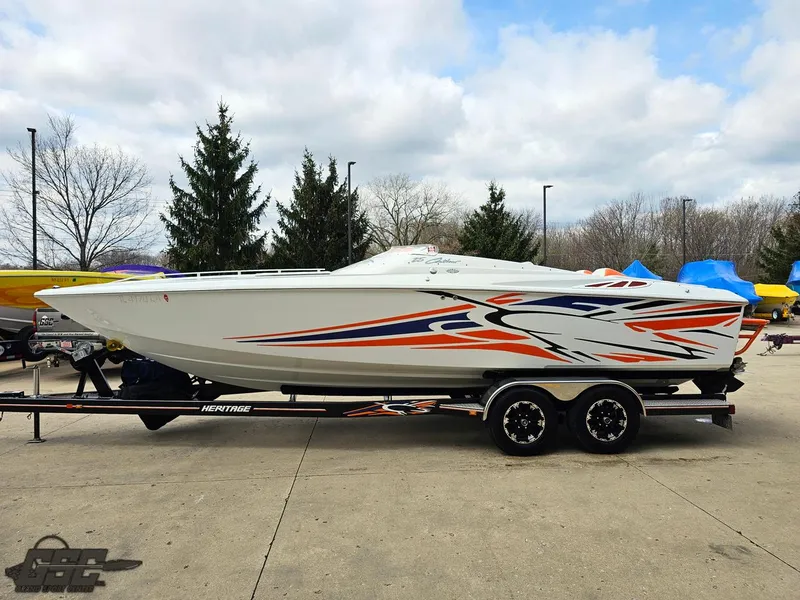 Slide: The Image of 2005 Baja 25 Outlaw speedboat with vibrant graphics on a trailer, parked outdoors. - 21