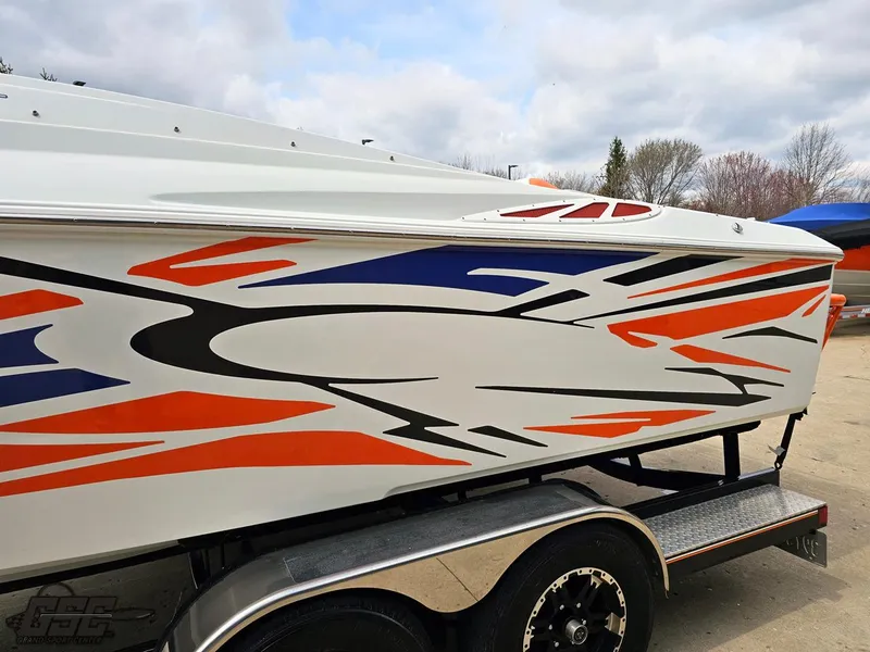 Slide: The Image of 2005 Baja 25 Outlaw boat with vibrant orange and blue graphics on a trailer. - 24