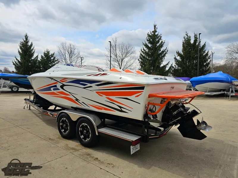 Slide: The Image of 2005 Baja 25 Outlaw speedboat with vibrant graphics on a trailer, parked outdoors. - 29