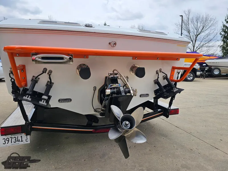 Slide: The Image of 2005 Baja 25 Outlaw boat stern with propeller and orange trim, parked on concrete. - 31