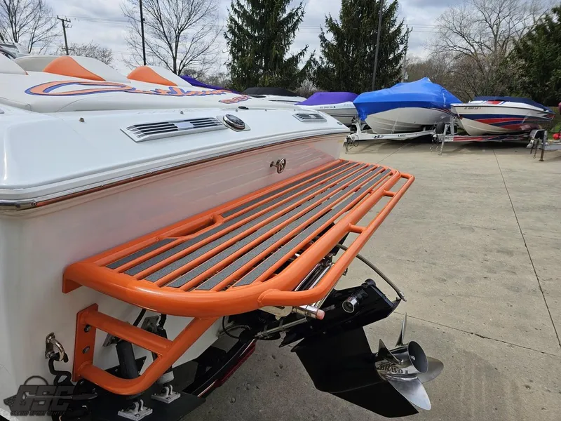 Slide: The Image of 2005 Baja 25 Outlaw boat with orange swim platform, parked outdoors. - 32