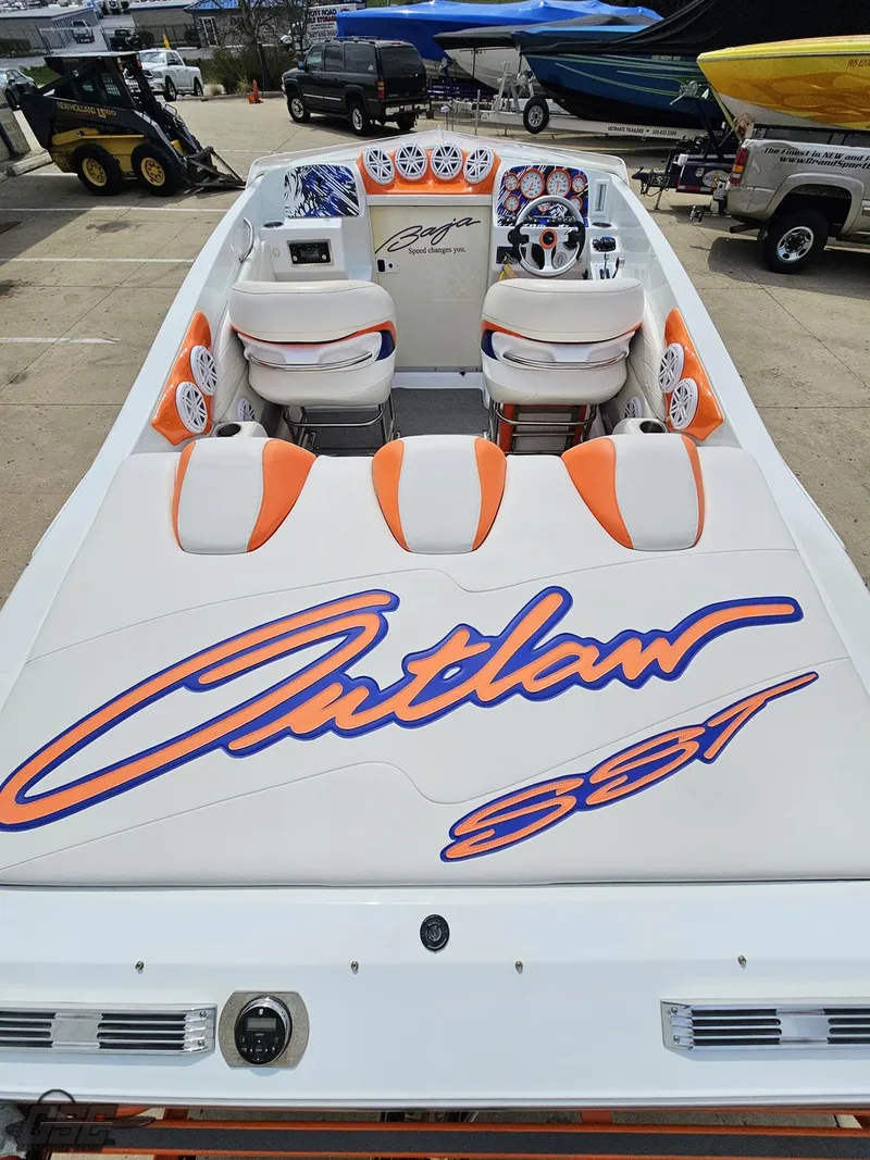 Slide: The Image of 2005 Baja 25 Outlaw speedboat with vibrant orange and white interior, docked outdoors. - 45